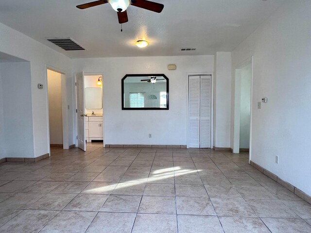 interior space featuring light tile patterned floors, sink, ceiling fan, and ensuite bathroom