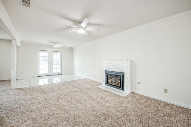 unfurnished living room featuring crown molding, a brick fireplace, light carpet, and french doors