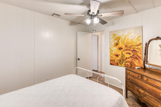 bedroom featuring ceiling fan, visible vents, and wood finished floors