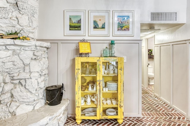 details featuring a wainscoted wall, a decorative wall, and visible vents