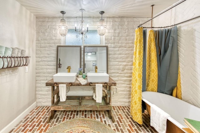 interior space featuring baseboards, a freestanding bath, a sink, and brick floor