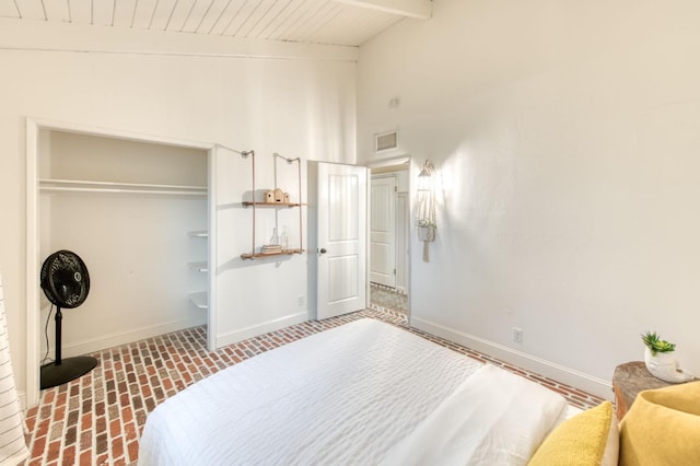 bedroom featuring wooden ceiling, brick floor, baseboards, and a closet