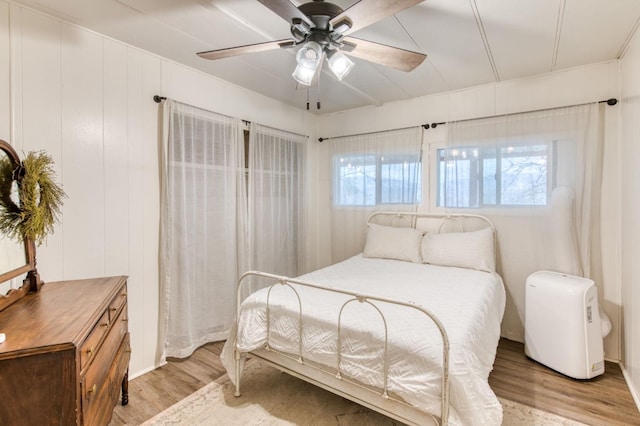 bedroom featuring a ceiling fan, multiple windows, and light wood-style flooring