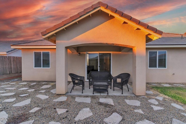 back house at dusk featuring a patio area