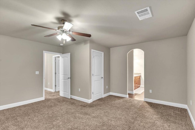 unfurnished bedroom with ensuite bathroom, ceiling fan, and carpet flooring