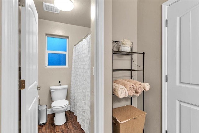 bathroom with hardwood / wood-style flooring, walk in shower, and toilet