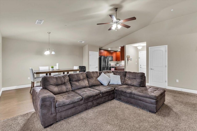 living room with hardwood / wood-style floors, vaulted ceiling, and ceiling fan with notable chandelier