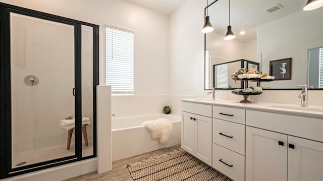 bathroom with plus walk in shower, hardwood / wood-style floors, and vanity