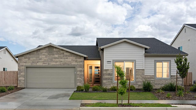 view of front facade featuring fence, an attached garage, driveway, and stone siding