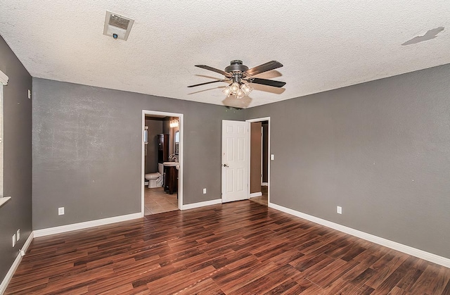 unfurnished bedroom with ceiling fan, dark hardwood / wood-style floors, ensuite bathroom, and a textured ceiling