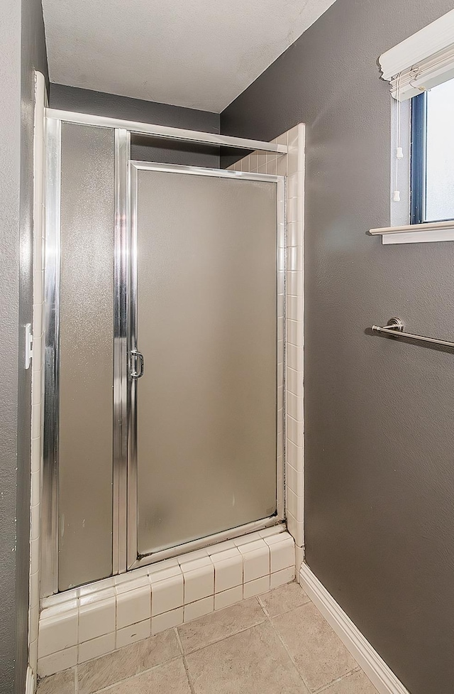 bathroom with a shower with door and tile patterned floors