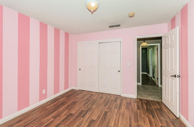 unfurnished bedroom featuring a closet, dark hardwood / wood-style floors, and a textured ceiling