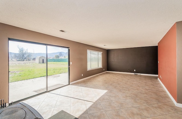 empty room with light tile patterned flooring and a textured ceiling