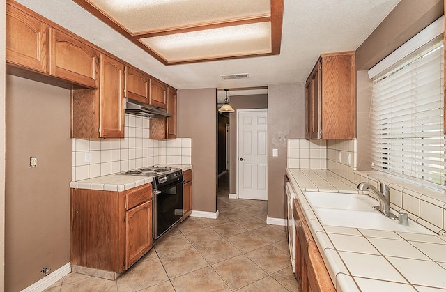 kitchen featuring black electric range oven, tile counters, decorative backsplash, and decorative light fixtures