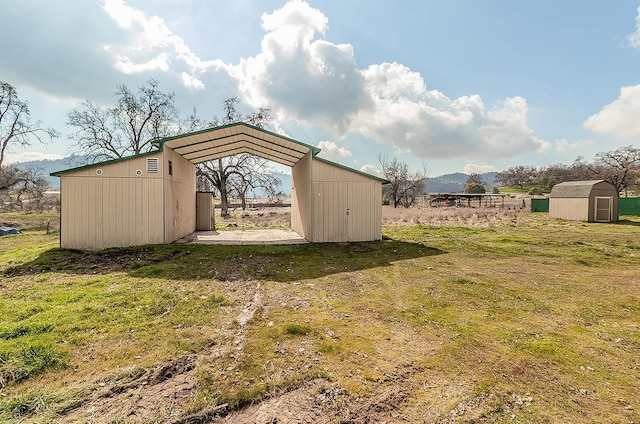 view of outdoor structure featuring a mountain view, a yard, and a rural view