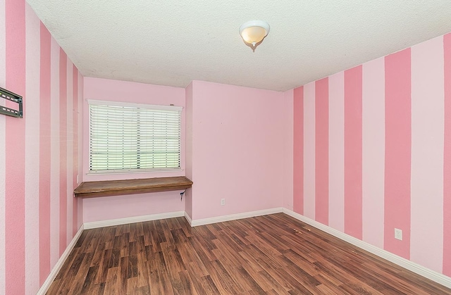 empty room with a textured ceiling and dark hardwood / wood-style flooring