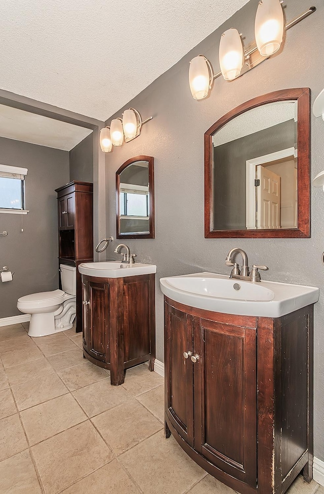 bathroom featuring vanity, tile patterned floors, a textured ceiling, and toilet