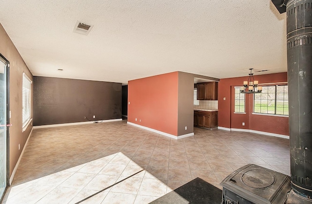 unfurnished living room featuring light tile patterned floors, a textured ceiling, and an inviting chandelier