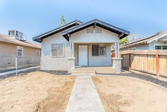 bungalow with fence and stucco siding