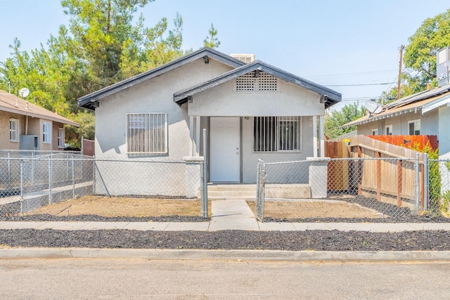 bungalow featuring a fenced front yard and stucco siding