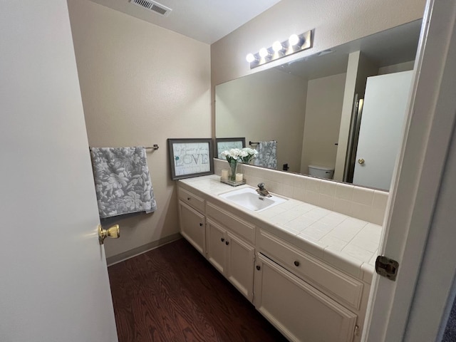 bathroom with wood-type flooring, toilet, vanity, and backsplash