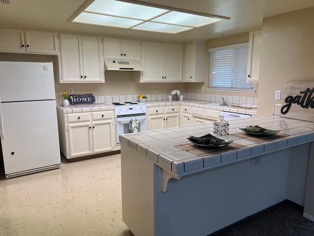 kitchen with white cabinetry, white appliances, tile countertops, and kitchen peninsula