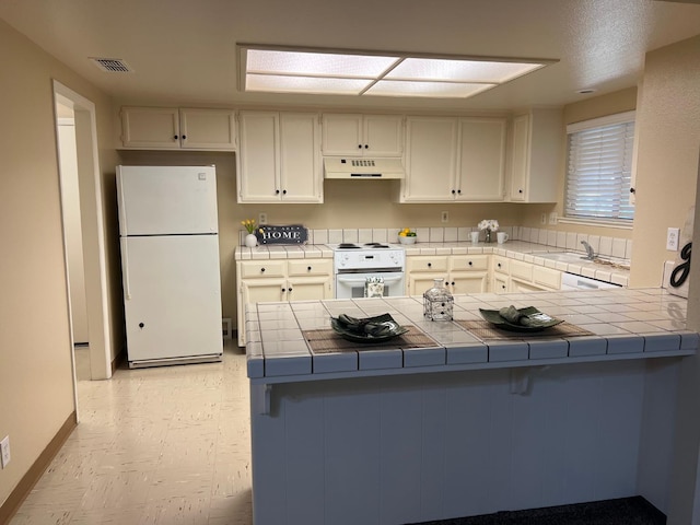 kitchen with white cabinetry, tile countertops, white appliances, and kitchen peninsula