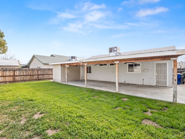 back of property with central AC unit, a lawn, and a patio