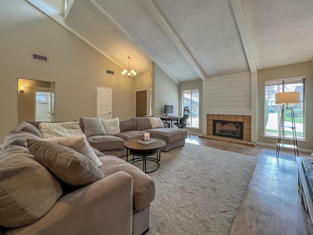 living room with a tiled fireplace, hardwood / wood-style flooring, plenty of natural light, and beam ceiling