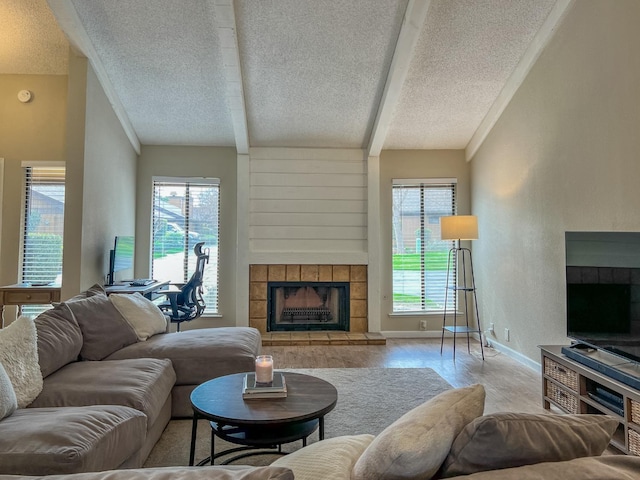 living room featuring a textured ceiling, a tile fireplace, a healthy amount of sunlight, and light wood-type flooring