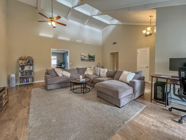 living room with ceiling fan with notable chandelier, lofted ceiling with beams, and light wood-type flooring