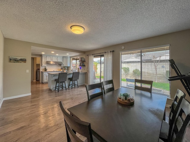 dining room with a textured ceiling and light hardwood / wood-style floors