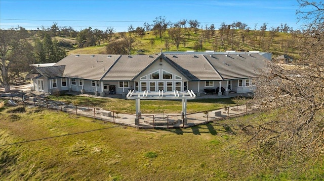 back of house featuring a fenced backyard, a tile roof, a yard, and a patio
