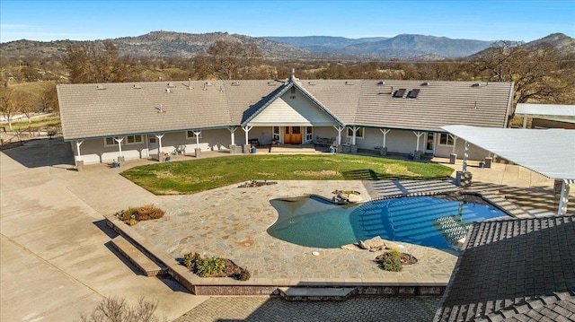 pool featuring a lawn, a patio, and a mountain view