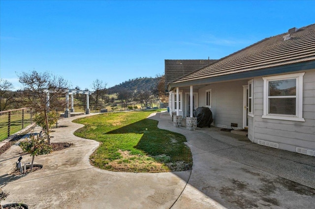 view of yard featuring fence, visible vents, a mountain view, and a patio