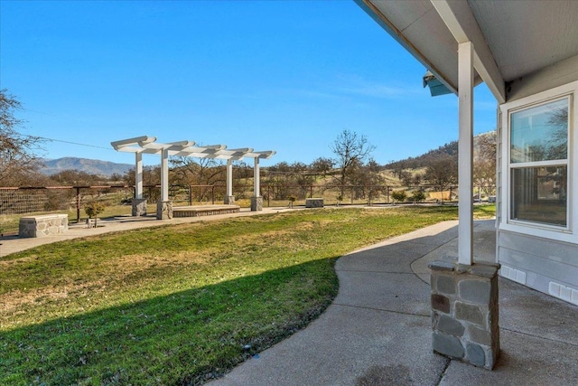 view of yard featuring a pergola, a patio area, fence, and a mountain view