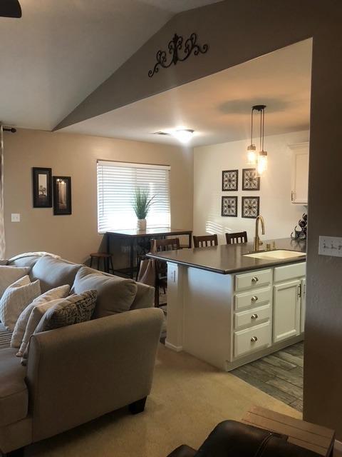 living room featuring vaulted ceiling, sink, and light carpet