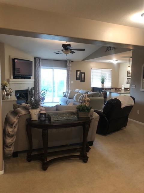 carpeted living room with a fireplace and ceiling fan