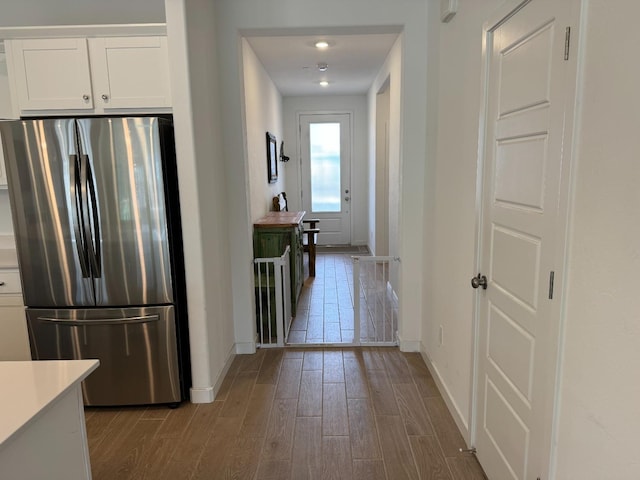 hallway with wood-type flooring and white cabinets