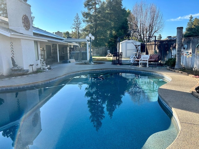 view of swimming pool with a shed and a patio