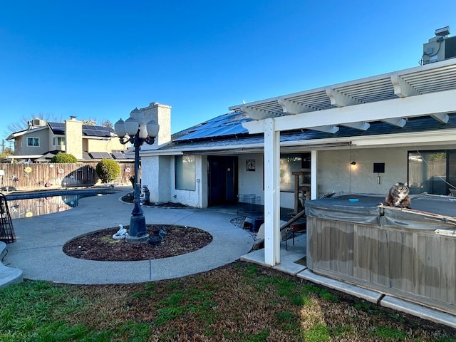 back of property featuring a swimming pool with hot tub, a pergola, a patio, and solar panels