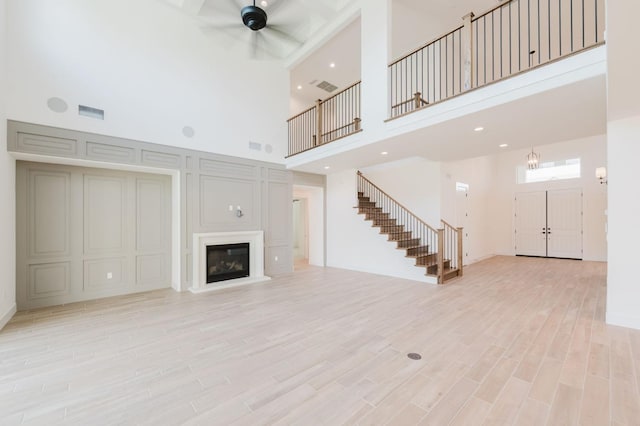 unfurnished living room with a towering ceiling and light hardwood / wood-style flooring