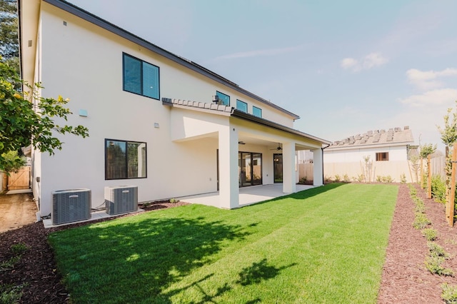 rear view of property with a lawn, central AC unit, and a patio area