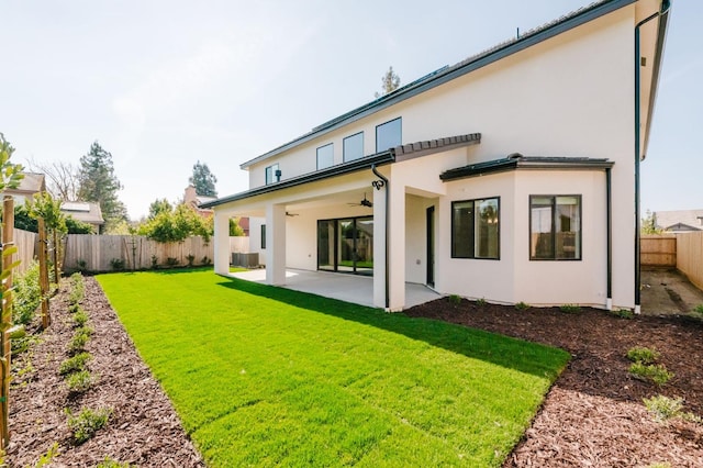 back of property with a lawn, ceiling fan, and a patio area