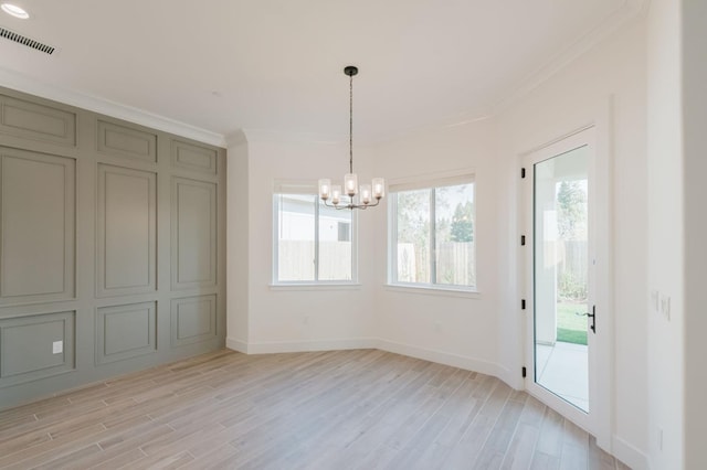 unfurnished dining area with crown molding, an inviting chandelier, and light hardwood / wood-style floors