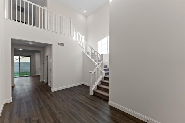 stairs featuring hardwood / wood-style floors and a high ceiling