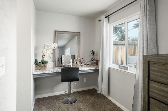 home office featuring built in desk, baseboards, a healthy amount of sunlight, and dark colored carpet