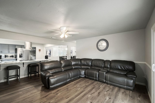 living room with baseboards, ceiling fan, and dark wood-style floors
