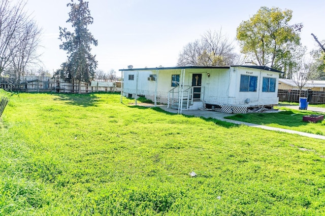 back of property featuring a lawn, entry steps, and fence