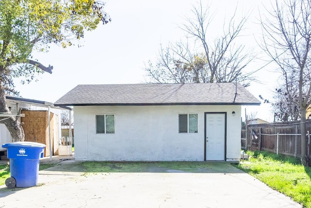 back of house with stucco siding, a patio, roof with shingles, and fence